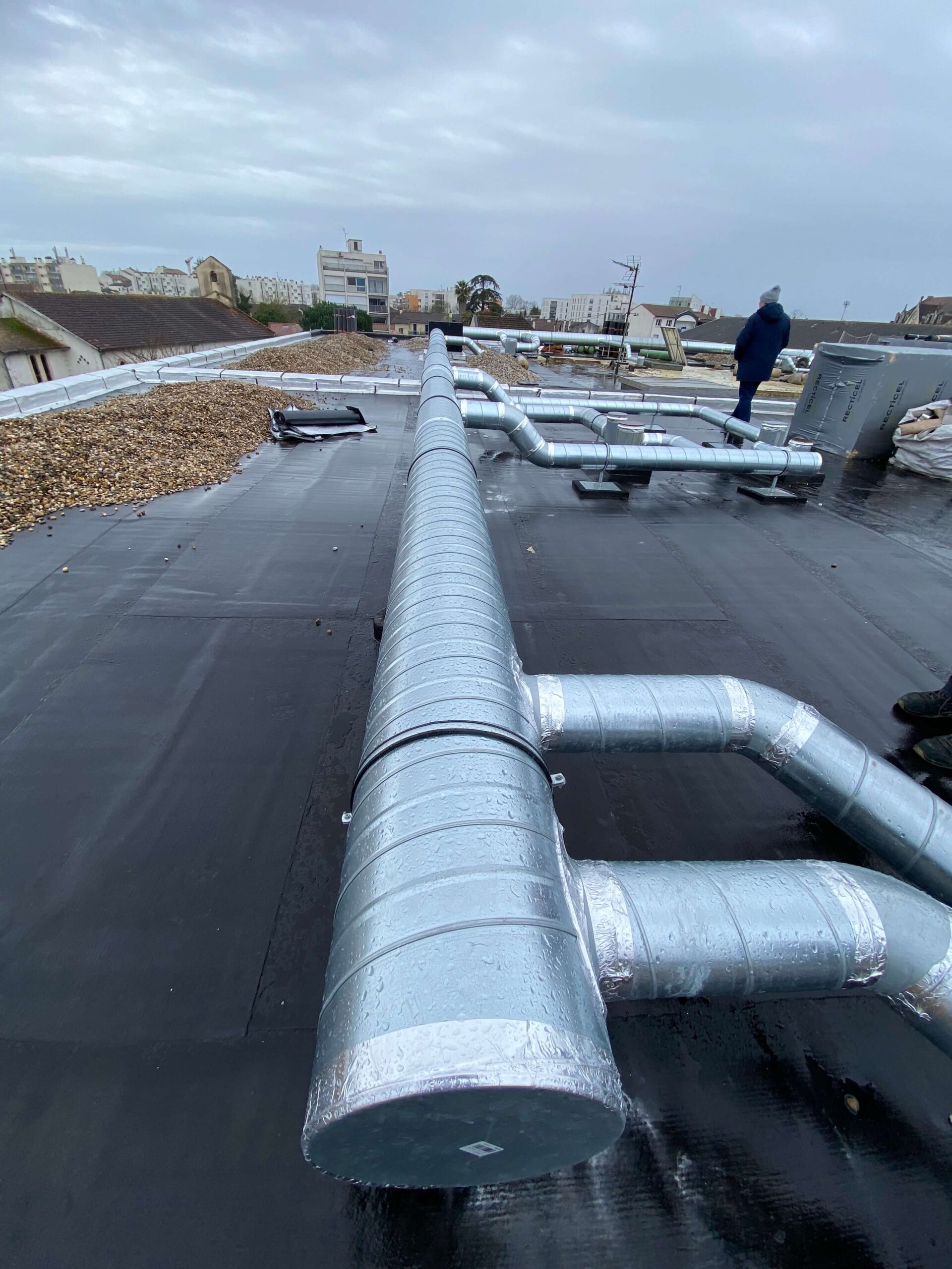 Gaine VMC neuve surélevée sur plots supports pour protéger l'étanchéité de la toiture-terrasse et faciliter la maintenance future.